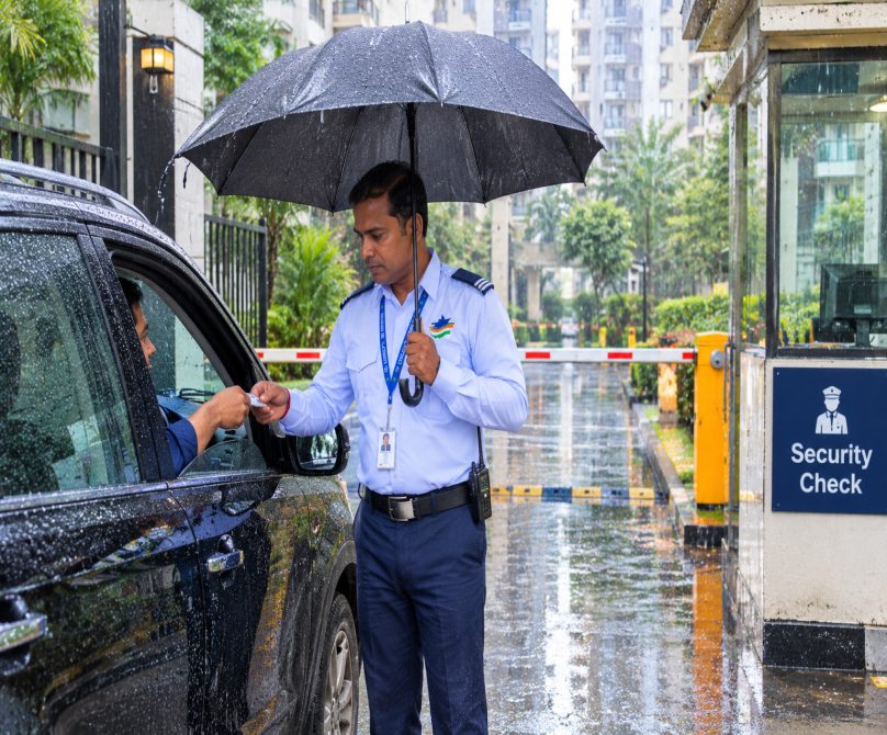 DB Security Services guard checking a vehicle at the gate in the rain